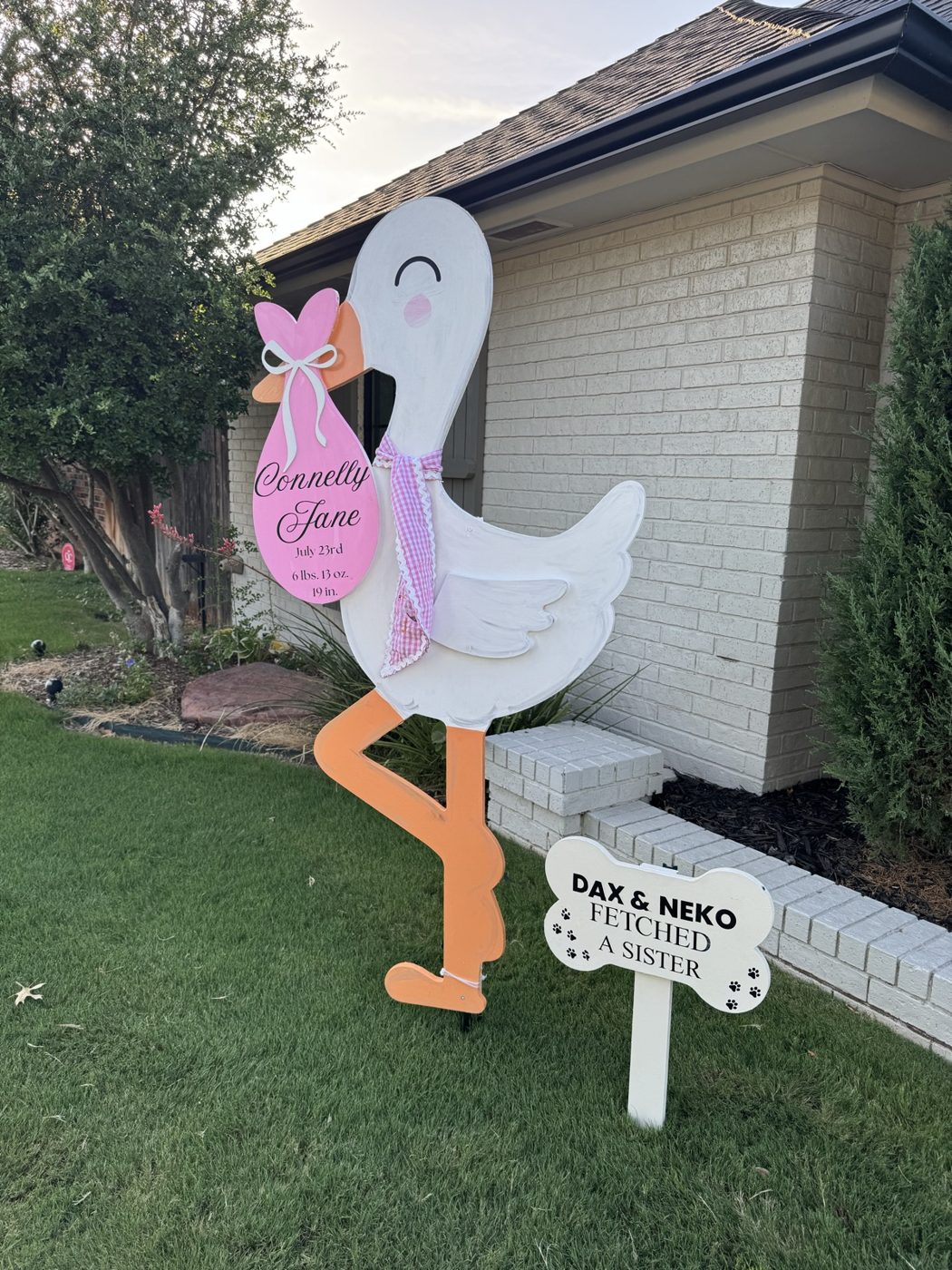 Stork yard sign with personalized pet signs on a front porch
